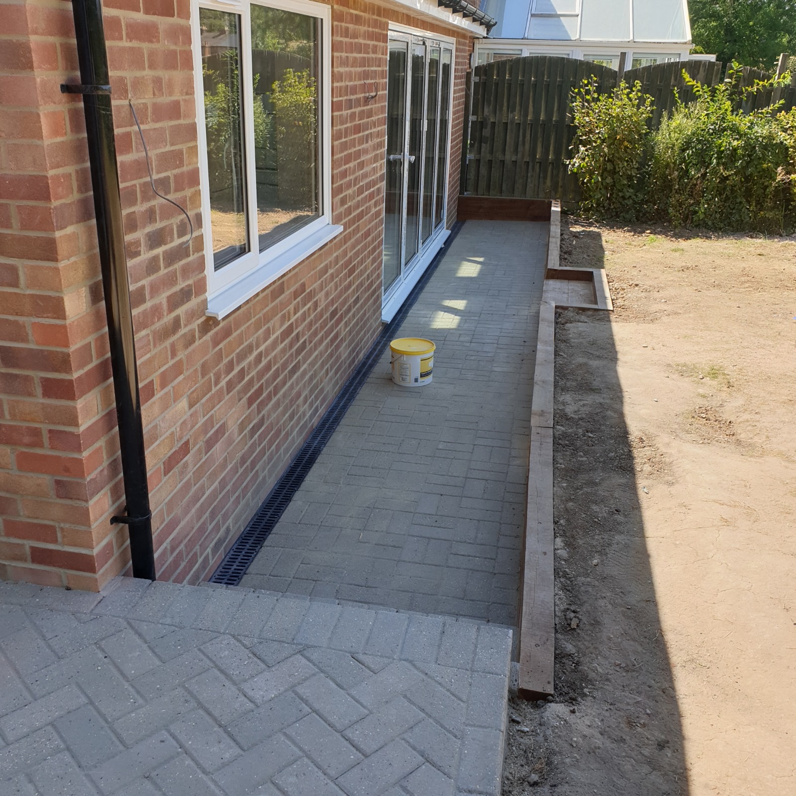 Rear extension in red brick with white uPVC patio doors, alongside newly laid block paving