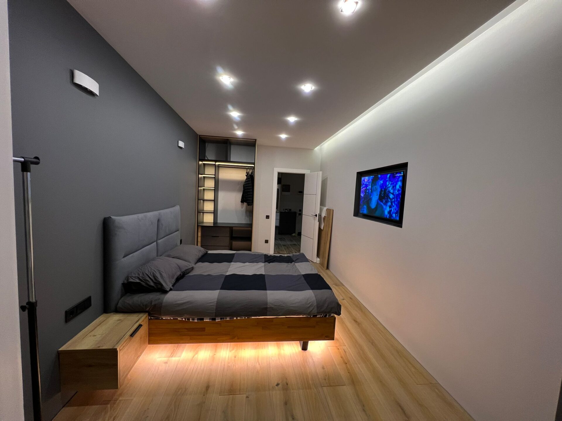 Refurbished bedroom with a grey feature wall and a low bed with recessed under-bed lighting