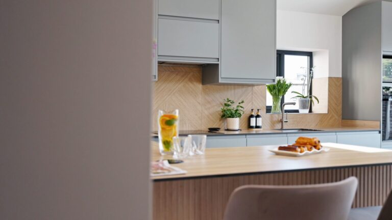 Pale blue kitchen with a wood-effect worktop, breakfast island and herringbone tiled splashback