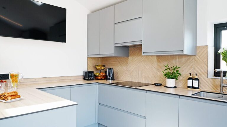 Handleless pale blue kitchen with an induction hob, wood worktop and herringbone splashback