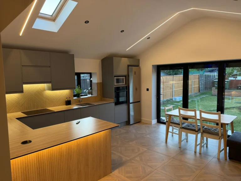 Kitchen with an oak-fronted island and bi-fold doors opening to the garden, with a dining table
