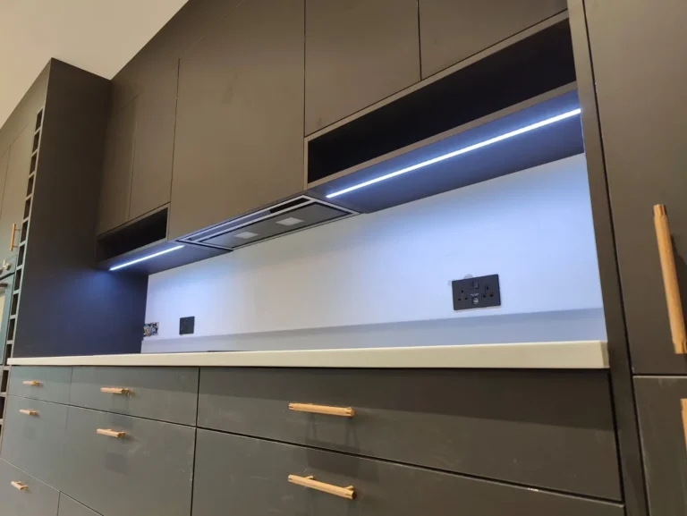 Close view of a grey handleless kitchen with an integrated extractor and lit splashback