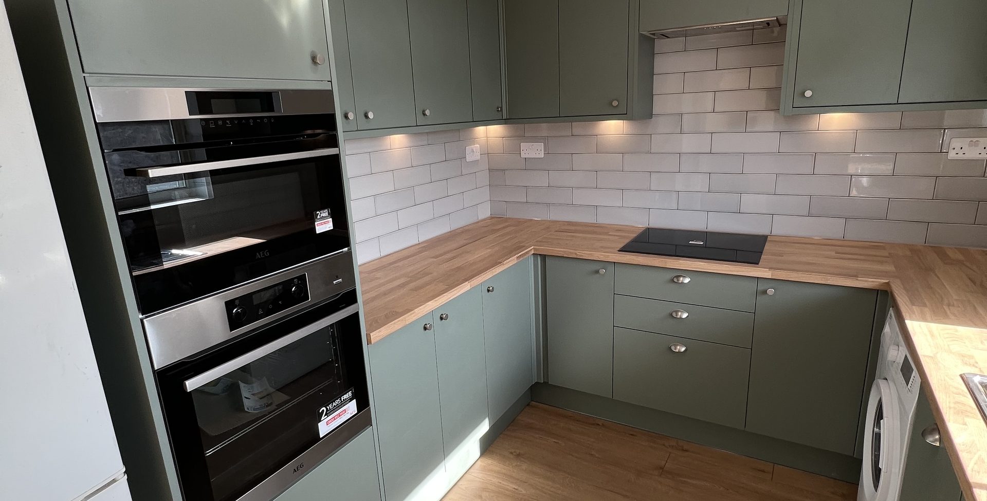 Finished kitchen near Erith, sage green units, solid wood worktop and a white metro tile splashback