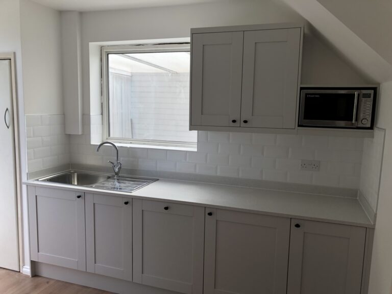 Refitted galley kitchen in Mottingham with grey shaker units, metro tiles and oak-effect floor