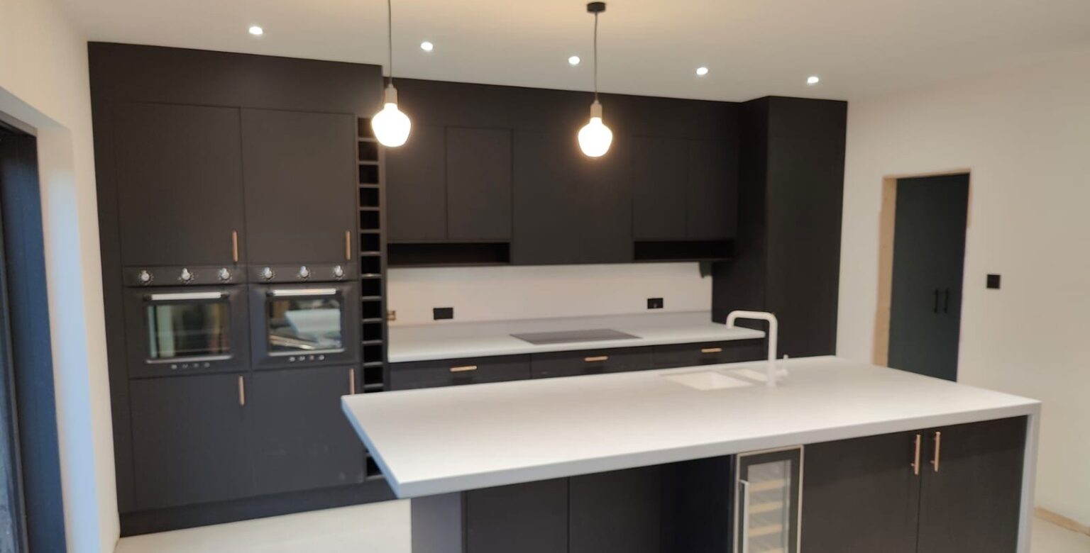 Finished kitchen extension with a dark island, pendant lights and a glazed lantern, built by Space Up in Beckenham