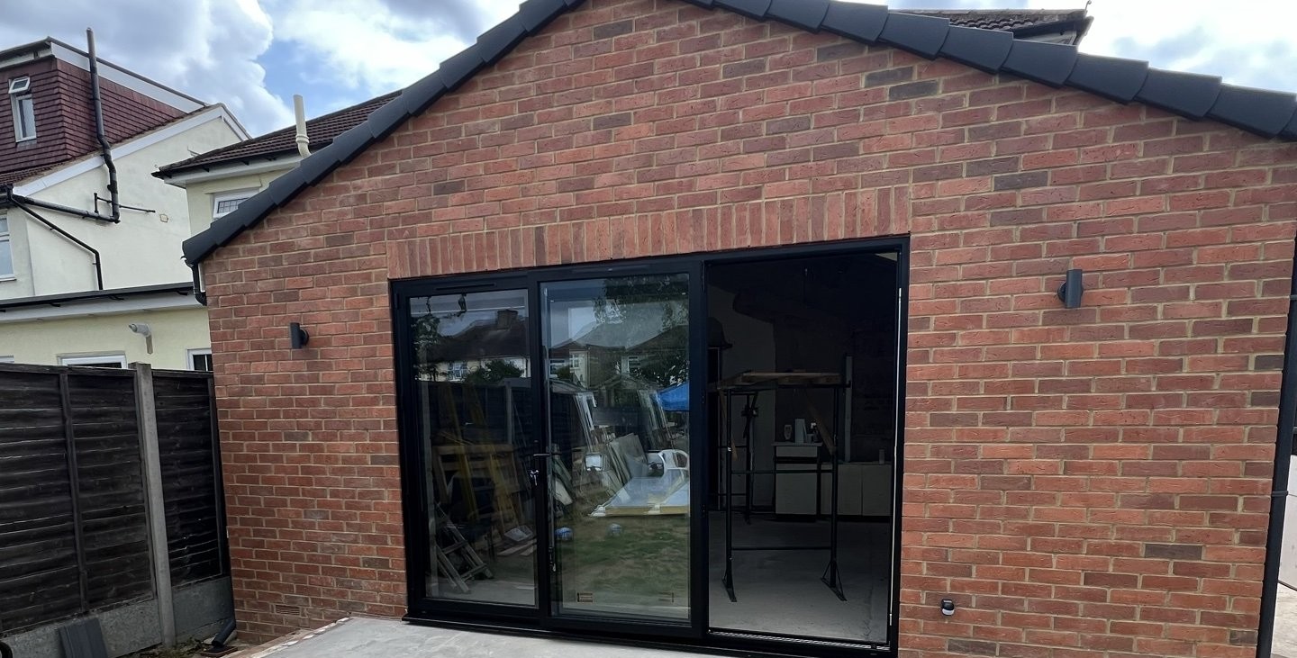 Completed brick rear extension with black sliding doors and a paved step onto the garden, 2.7 miles from Sidcup